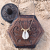 Simple handmade cowrie shell necklace with brass beads on white background