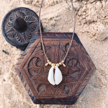 Simple handmade cowrie shell necklace with brass beads on white background