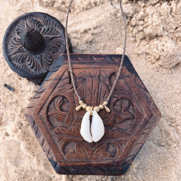 Simple handmade cowrie shell necklace with brass beads on white background
