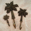 Antique brass coconut palm wall hooks in small medium and large sizes on linen background
