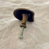 Antique brass scallop shell drawer knob back view showing turned brass stem and screw fitting on linen
