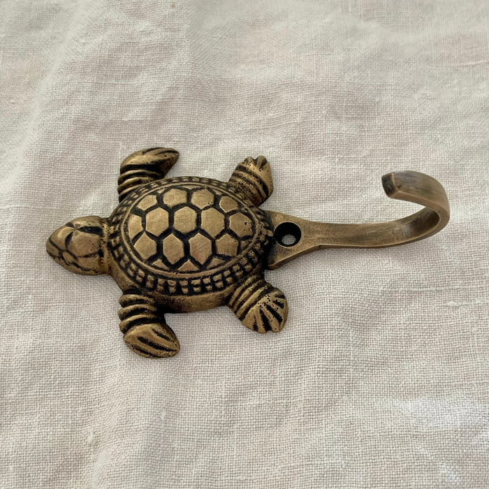 Antique brass sea turtle wall hook side angle showing hook arm and shell detail on linen background
