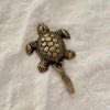 Antique brass sea turtle wall hook top view showing detailed hexagonal shell pattern and textured flippers on linen
