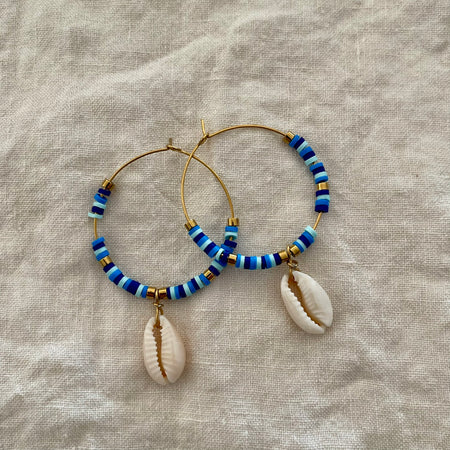 Mixed blue polymer clay bead hoop earrings with natural cowrie shell drop and gold-tone accents
