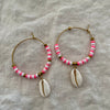 Pink and white polymer clay bead hoop earrings with natural cowrie shell drop on linen background
