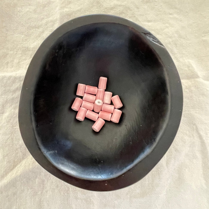 Blush pink ceramic barrel beads in a dark bowl - Travel and Tide Coastal Notions.
