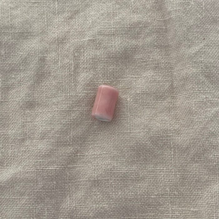 Blush pink ceramic barrel bead on white linen - Travel and Tide Coastal Notions
