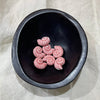 Blush pink ceramic nautilus shell beads in a dark bowl - Travel and Tide Coastal Notions
