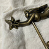 Detail of brass mermaid figure holding a starfish on antique brass wall hook
