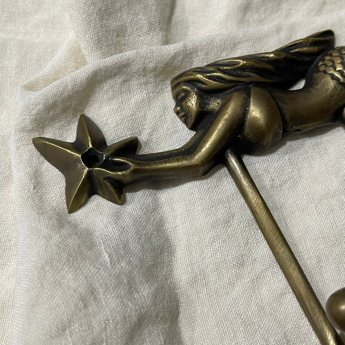 Detail of brass mermaid figure holding a starfish on antique brass wall hook
