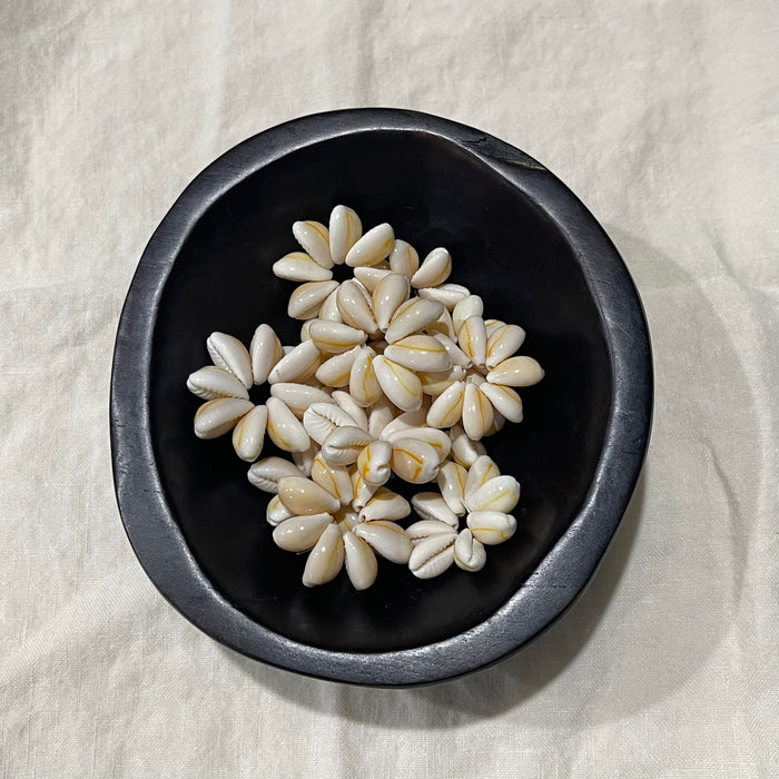 White cowrie shell flower charms in a dark bowl - Travel and Tide Coastal Notions
