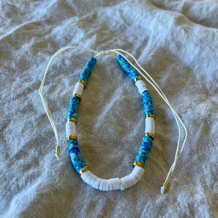 Dark blue polymer clay bead anklet with gold-tone rings and white shell beads on adjustable white cord

