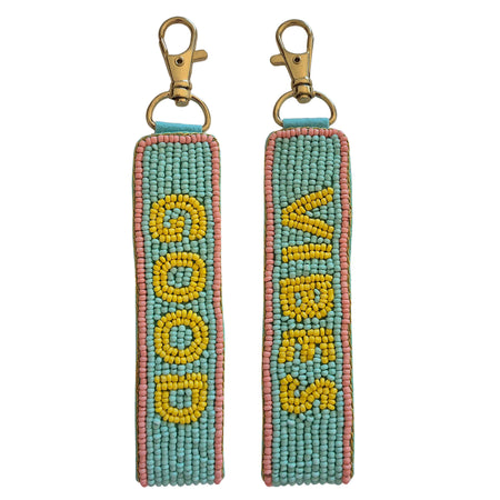Front and back views of an aqua beaded keychain with yellow GOOD and VIBES lettering, pink edging and a gold-tone clasp
