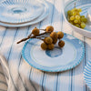 Blue and white cockle shell patterned plates with fruits on a striped tablecloth