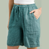 100% linen Bermuda shorts in duck green with pom-pom trim hem and drawstring waist worn by model
