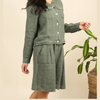 100% linen wide-leg Bermuda shorts in duck green front view worn by model with linen jacket and tropical plant
