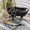 Maya black mango wood footed bowl with matte finish styled on a coastal sideboard