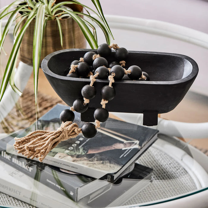 Maya black mango wood footed bowl with matte finish styled on a coastal sideboard