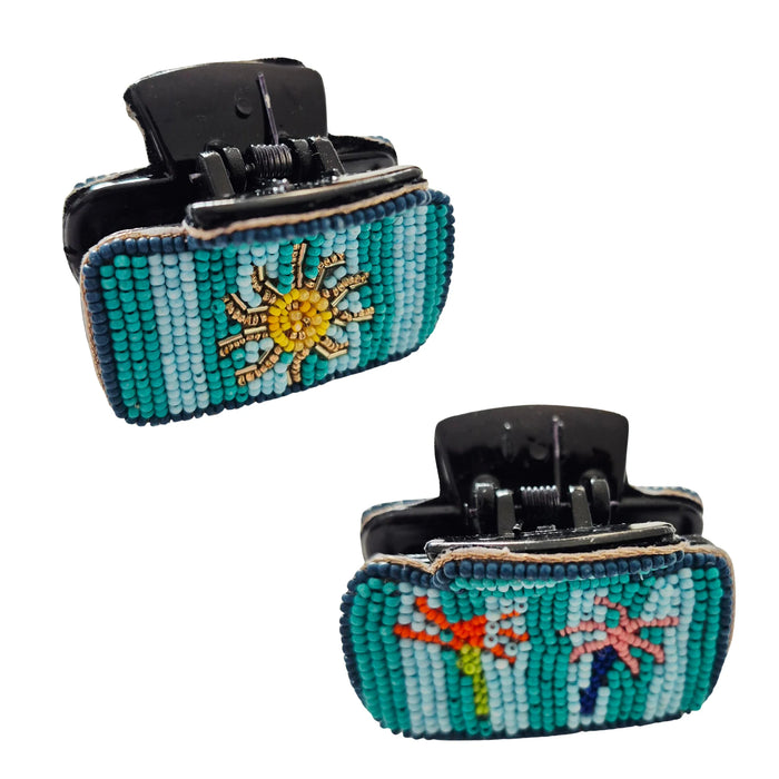 Two views of a black hair claw clip with blue and turquoise beaded stripes, a yellow sun on one side and colourful palm trees on the other
