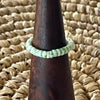 Sage green shell disc stretch ring on wooden cone display, soft mint green shell beads on elastic band
