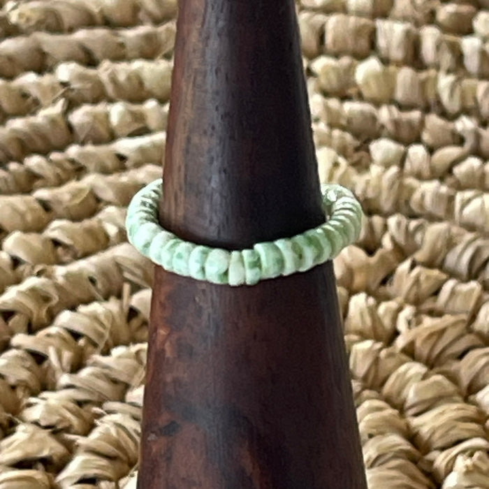 Sage green shell disc stretch ring on wooden cone display, soft mint green shell beads on elastic band
