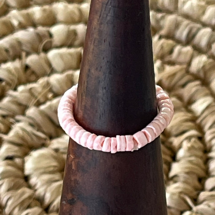 Pink pastel shell disc stretch ring on wooden cone display, soft blush tone shell beads on elastic band
