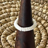 White shell disc stretch ring on wooden cone display, natural white shell beads threaded on elastic band

