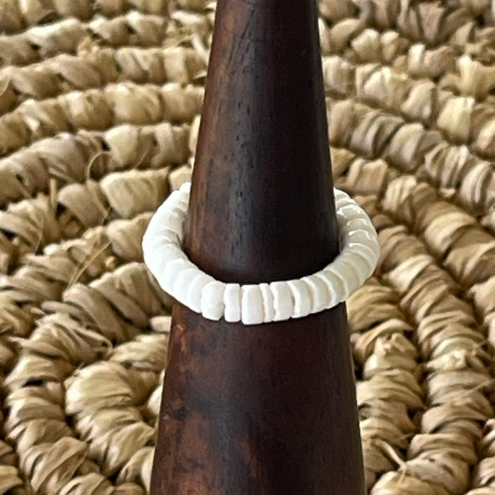 White shell disc stretch ring on wooden cone display, natural white shell beads threaded on elastic band
