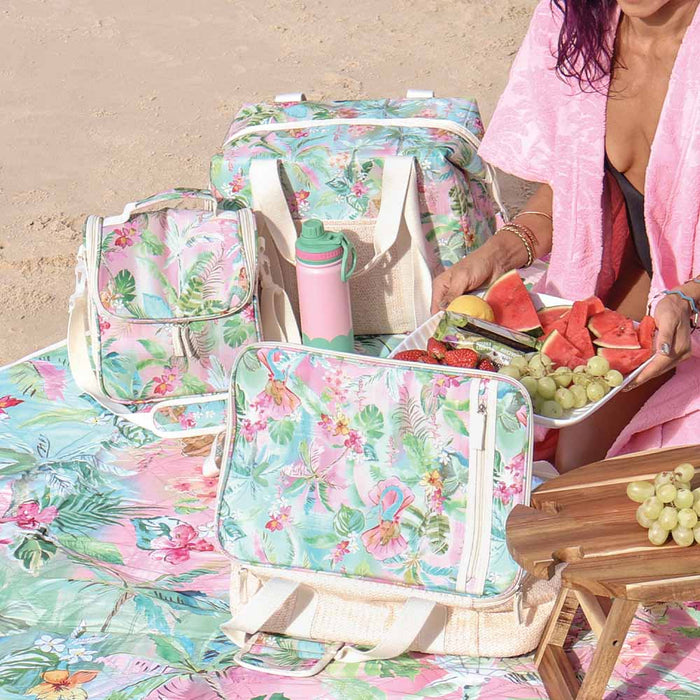 Tiki Island insulated picnic lunch bag styled on a picnic blanket outdoors with food and drinks
