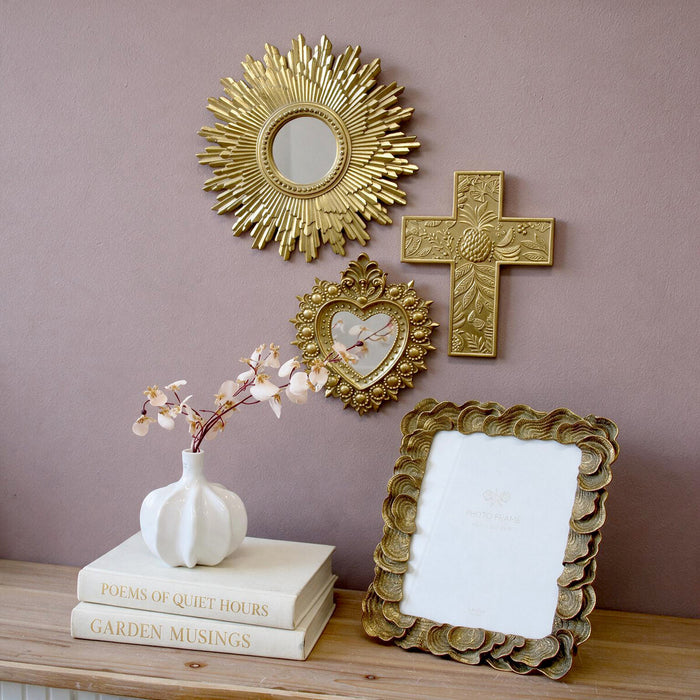 Gold sacred heart wall mirror styled in gallery wall grouping with sunburst mirror and cross wall art above timber console
