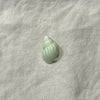 Seafoam green ceramic conch shell bead on white linen - Travel and Tide Coastal Notions
