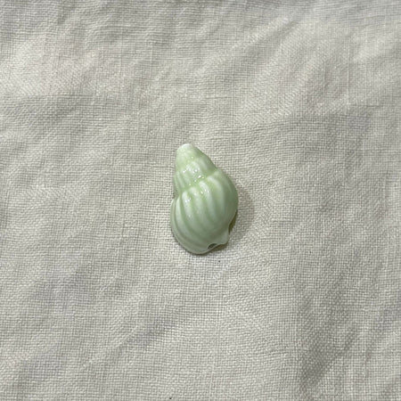 Seafoam green ceramic conch shell bead on white linen - Travel and Tide Coastal Notions
