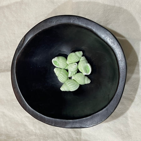 Seafoam green ceramic conch shell beads in a dark bowl - Travel and Tide Coastal Notions
