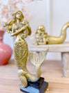 Gold resin standing mermaid sculpture styled on timber shelf with laying mermaid and pink vase
