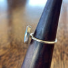 Sterling silver seaglass ring on wooden cone, angled top view showing slim hammered band profile and bezel edge detail
