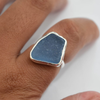 Sterling silver blue seaglass ring worn on hand, showing fit and scale of the freeform deep blue seaglass stone in bezel setting

