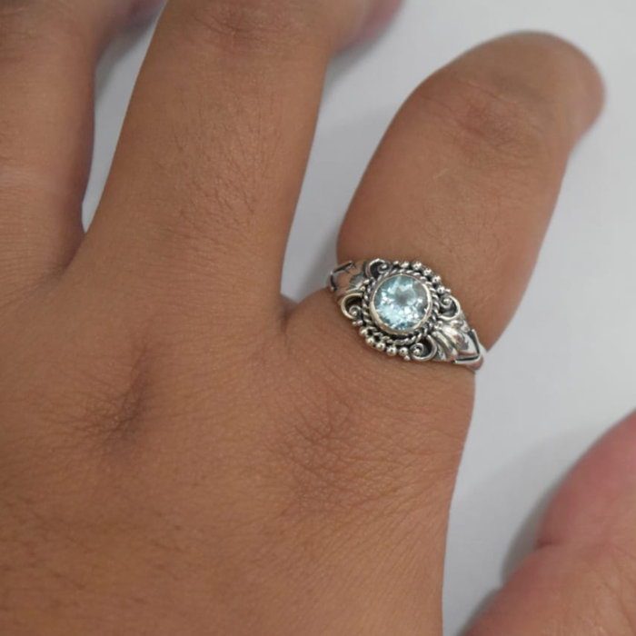 Sterling silver blue topaz detailed ring worn on hand, showing fit and scale of the round-cut blue topaz with Bali-inspired rope-twist and scrollwork setting
