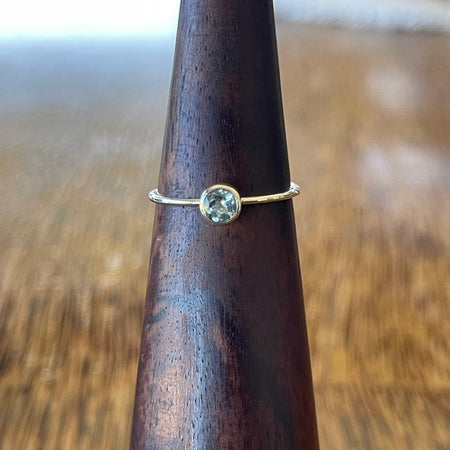 Sterling silver blue topaz stacking ring on wooden cone, side angle showing slim hammered band profile and bezel setting depth
