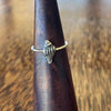 Sterling silver conch shell ring on wooden cone, front view showing textured oxidised shell with ridge and bead detail
