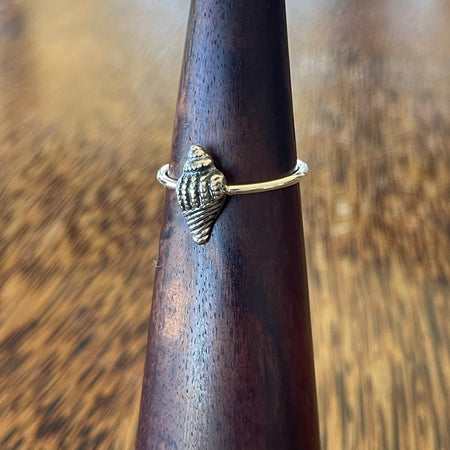 Sterling silver conch shell ring on wooden ring cone, side view showing oxidised shell detail and slim stacking band
