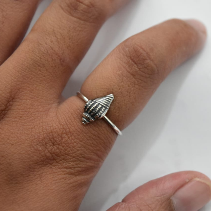 Sterling silver conch shell ring worn on hand, showing scale and fit of the oxidised shell detail on slim band
