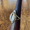Sterling silver cowrie ring on wooden cone, side angle showing bead edging, scallop shell motifs and slim split band
