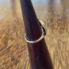 Sterling silver cowrie shell ring on wooden cone, angled side view showing split band and scallop shell detail at base of setting

