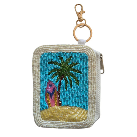 Rectangular beaded keychain pouch with a colourful surfboard, green palm tree, turquoise background, sandy-yellow base and cream border
